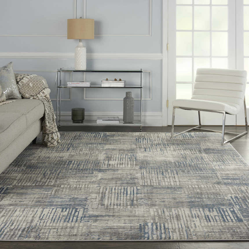 Modern living room with a Nourison Solace Ivory Grey Blue rug, sofa, and white chair.