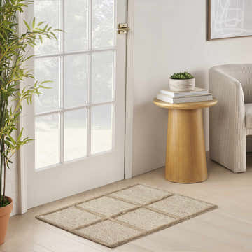 Entryway with a DKNY Pure Framework Camel rug, wood floors, white door, side table, and neutral chair.
