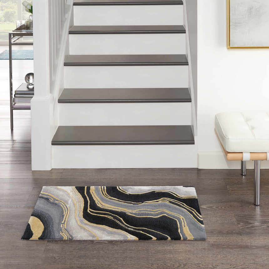 Entryway scene with Nourison Prismatic Charcoal Grey rug, white stairs, wood floors, and modern white bench.