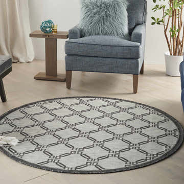Living room scene with a round Nourison Country Side Ivory/Charcoal rug, blue chair, and light wood floors.