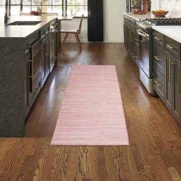 Modern kitchen with Nourison Essentials Pink runner rug on wood floor between dark cabinets.