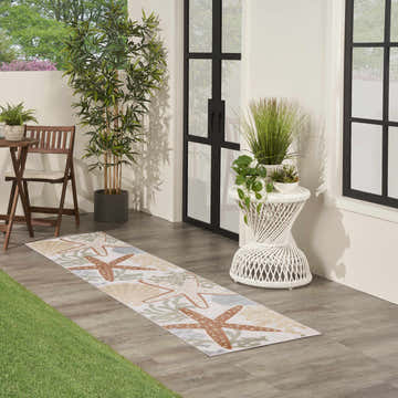Outdoor patio scene with Nourison Aloha Ivory Multicolor rug, starfish and seashell design.
