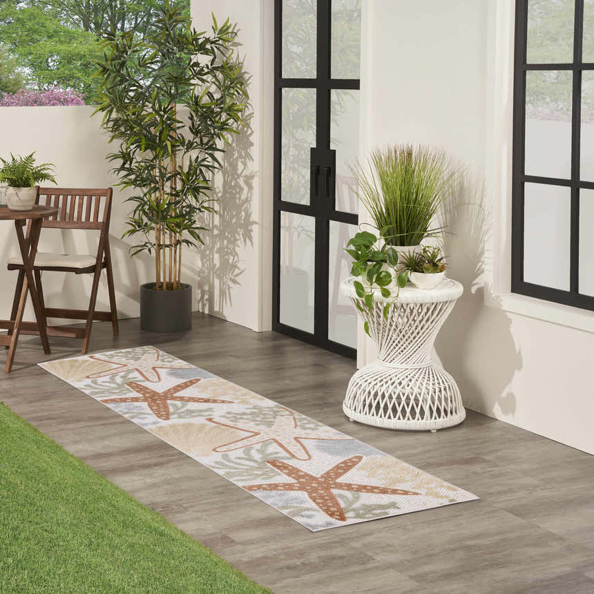 Outdoor patio scene with Nourison Aloha Ivory Multicolor rug, starfish and seashell design.