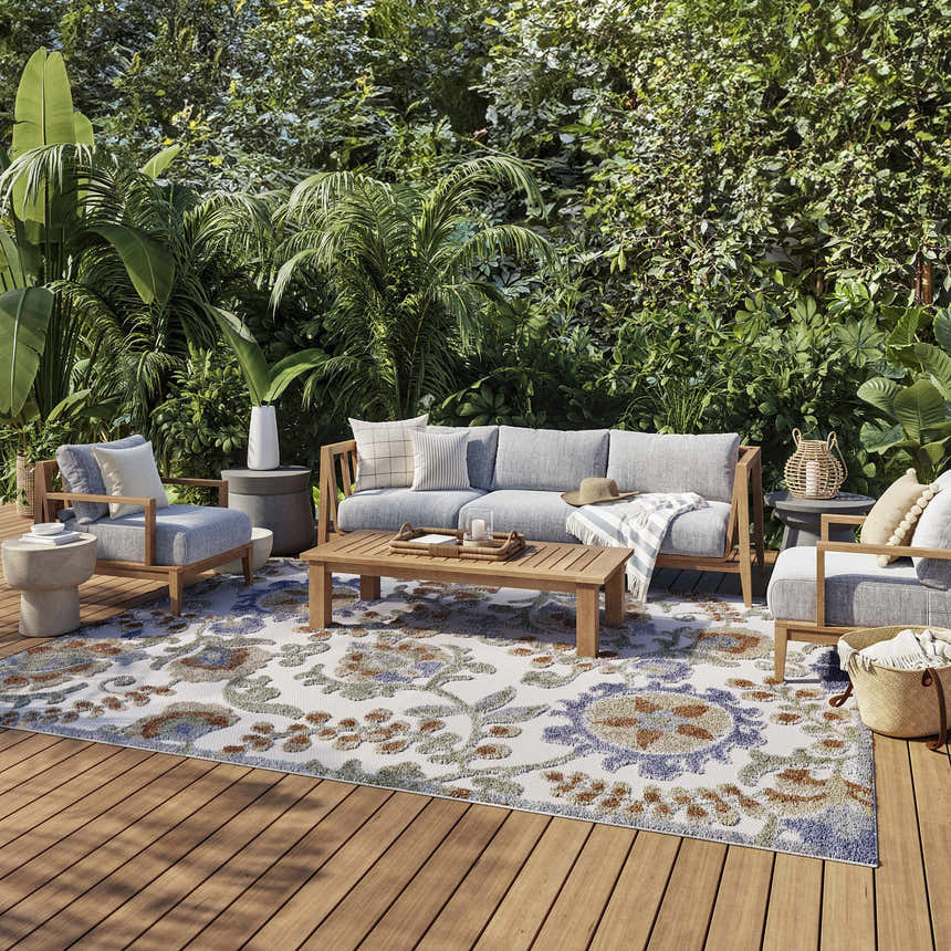 Outdoor patio with gray furniture and Nourison Aloha Ivory Blue Outdoor Area Rug on wood deck.