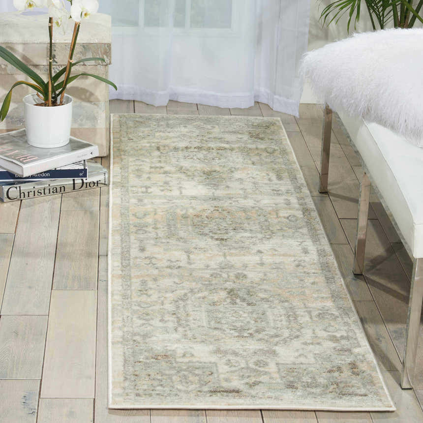 Light and airy room scene with Nourison Euphoria Ivory Persian rug, white bench, orchid, and sheer curtains.