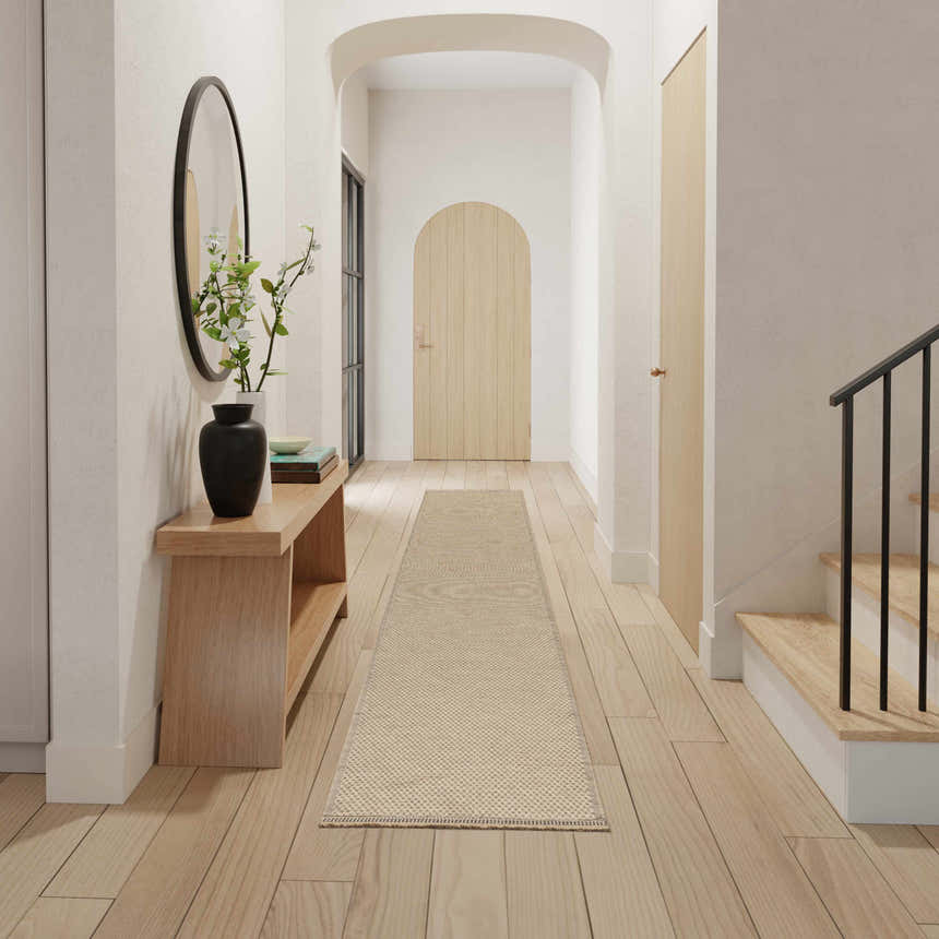 Entryway with a Nourison Jute Natural runner rug. Wood floors, bench, and arched doorway create a modern, neutral space.