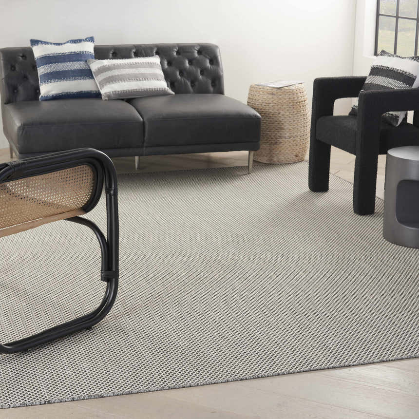 Modern living room with a black leather sofa and the Nourison Courtyard Ivory Charcoal Area Rug.