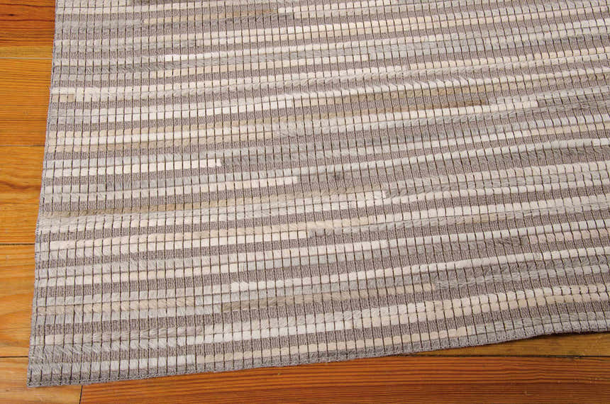 Close-up of the handmade Nourison Capelle Silver rug, with leather and wool stripes and a mid-century modern design.