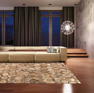 Modern living room with a beige sofa and Michael Amini City Chic Amber Gold rug featuring a geometric hexagon pattern.
