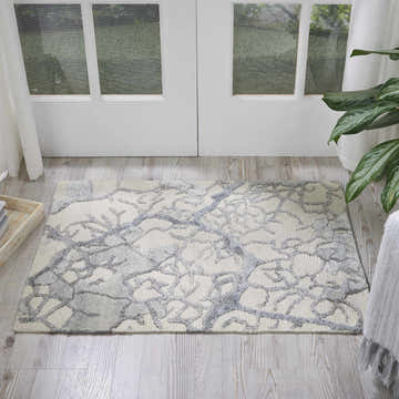 Light-filled room featuring a Nourison Divine Ivory rug with a chestnut branch pattern on wood floor near a white door.
