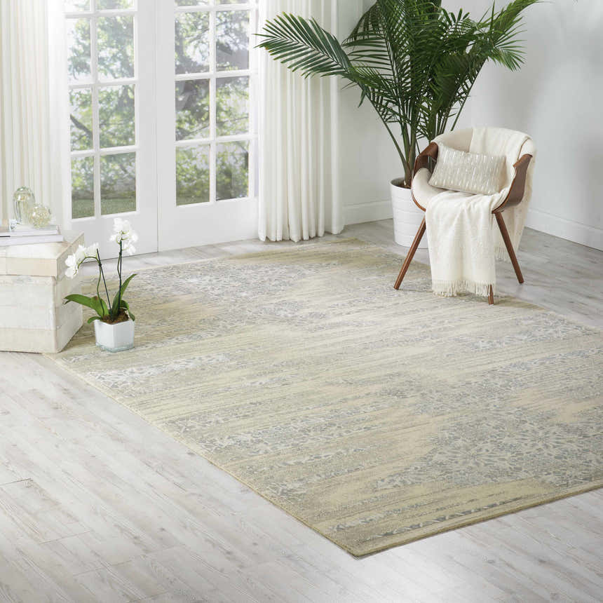 Sunlit room with the Nourison Luminance Bone Vintage rug, wood chair, and potted plants creating a serene, neutral-toned space.