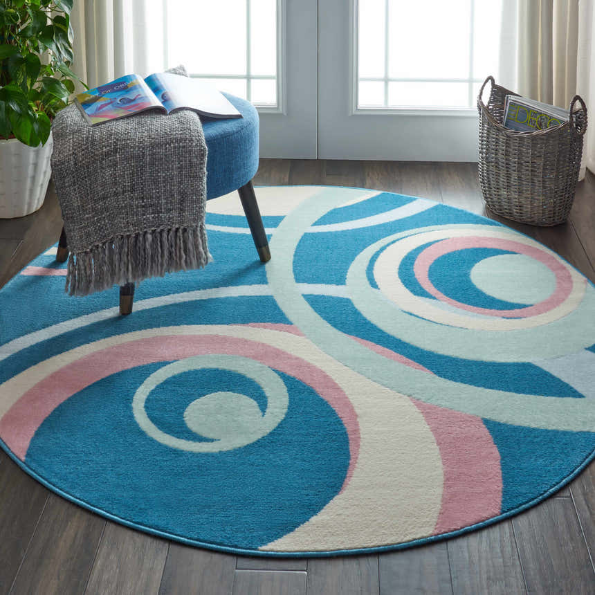 Living room scene with round Nourison Grafix Blue Multicolor rug, blue ottoman, and neutral decor.