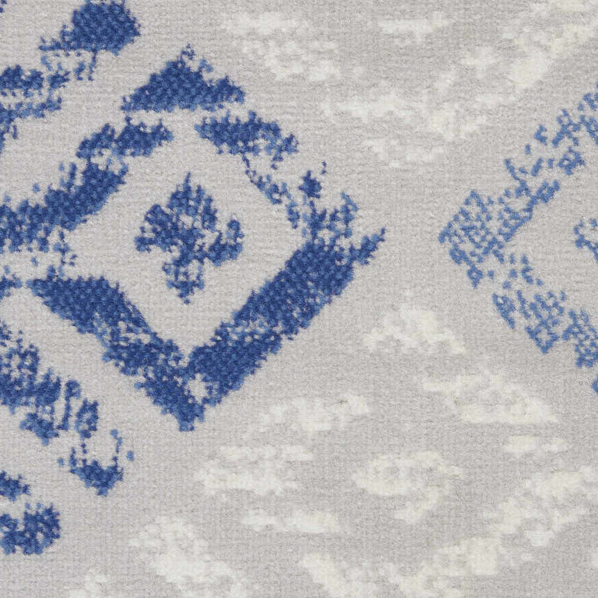 Close-up of the Nourison Whimsicle rug, featuring a grey background and a geometric blue bohemian pattern.