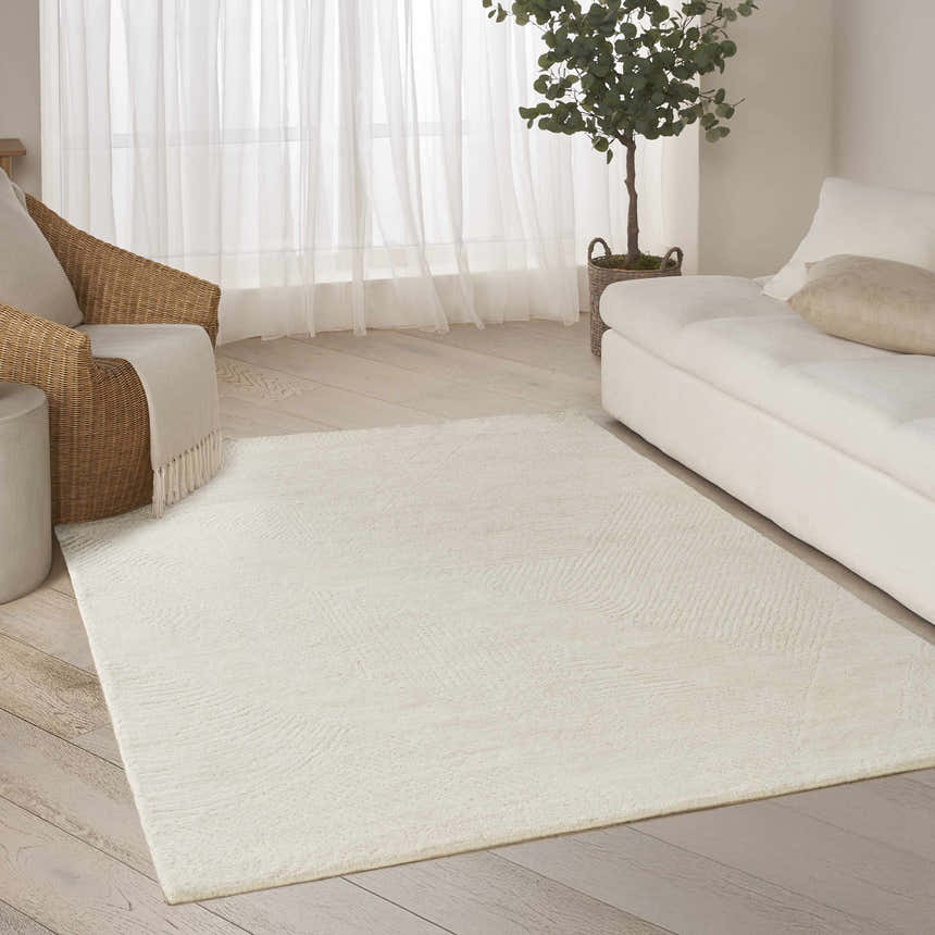Bright living room with a DKNY Pure Patterns Ivory rug, wicker chair, white sofa, and hardwood floors.