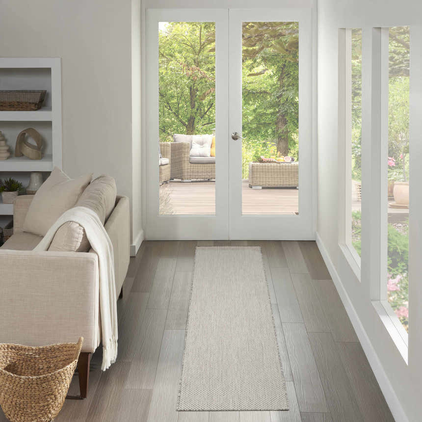 Light-filled hallway with a Nourison Courtyard Ivory Silver runner rug leading to an outdoor patio.