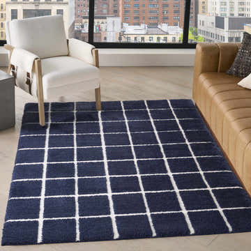 Living room scene with DKNY West End Ave Navy Ivory rug, white chair, and tan leather sofa.