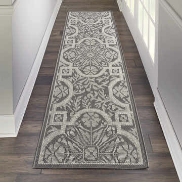 Hallway with Nourison Aruba Ivory/Grey Beach Area Rug runner on dark wood floors. White walls and door frame.