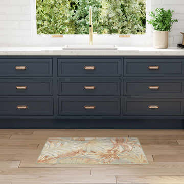 Kitchen scene with navy cabinets and Nourison Aloha Sage Rose Modern Area Rug on wood floor.