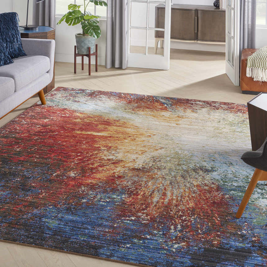 Living room scene with a Nourison Chroma Red Flare rug, gray sofa, and wood accents for a mid-century modern vibe.