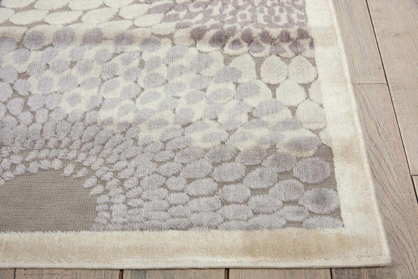 Close-up of the Nourison Graphic Illusions rug. Grey, cream, and white circle pattern, mid-century modern style. Soft texture.