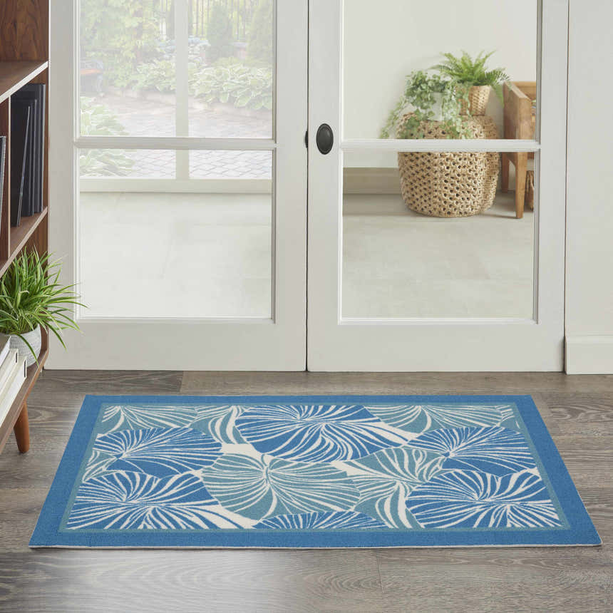 Entryway with Waverly Sun N' Shade Blue Tropical Area Rug. Light blue rug with tropical leaf pattern on wood floor.