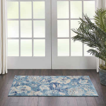 Room scene with Nourison Tranquil Turquoise Vintage rug, white french doors, dark wood floors, and potted palm.