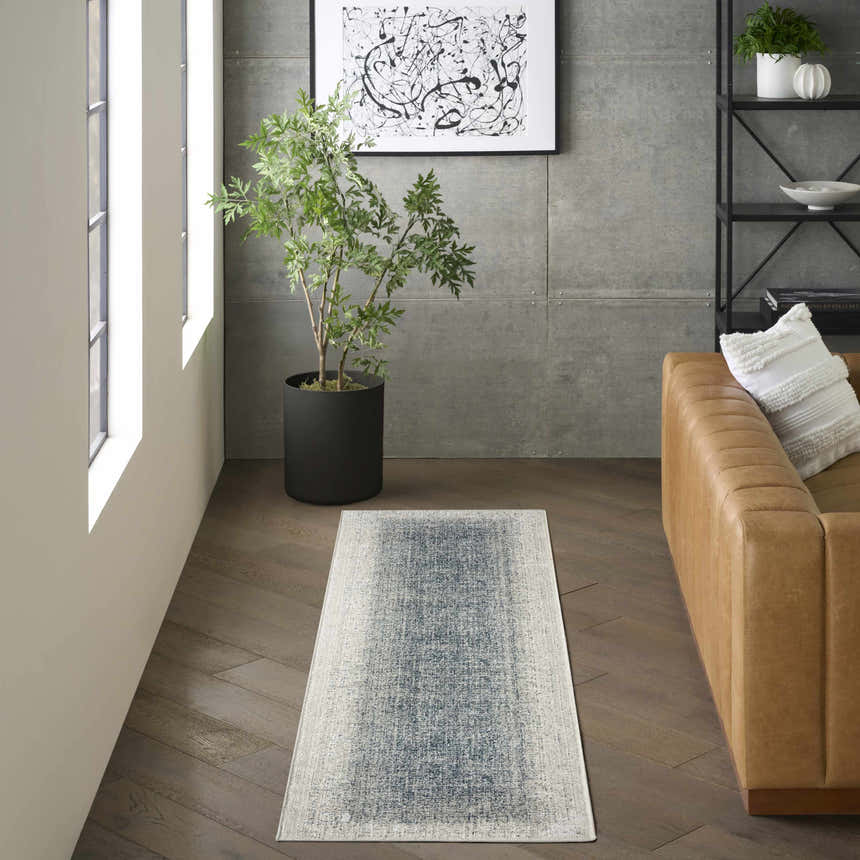 Modern living room with a chestnut leather sofa and DKNY Grand Street Ivory Blue Area Rug runner.