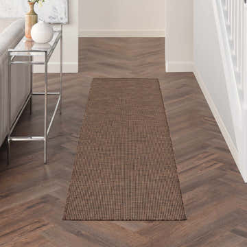 Hallway scene with a brick red Nourison Positano Natural Modern Area Rug runner on herringbone wood floors.