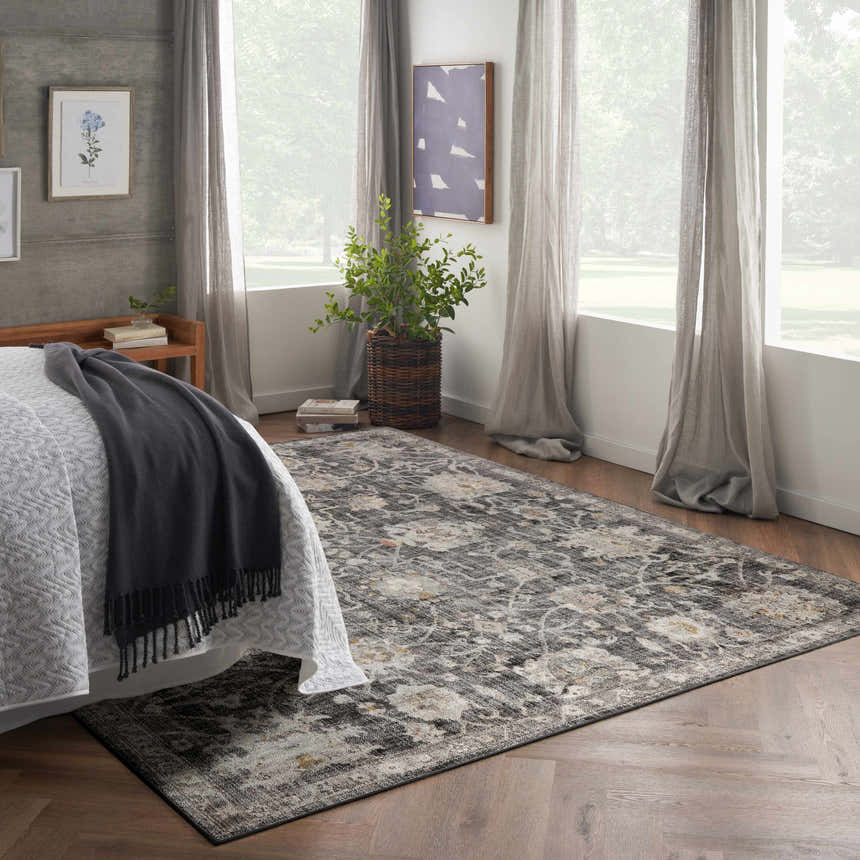 Serene bedroom with a Nourison Oushak Home Charcoal rug, wood floors, soft gray curtains, and natural light.