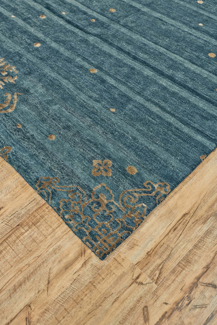 Close-up of Feizy Qing rug. Blue striped rug with tan floral border detail on light wood floor. Corner