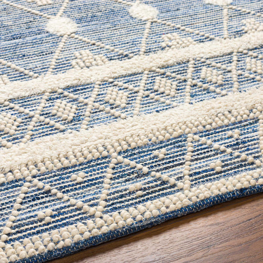 Close-up of Eben Area Carpet showing a blue and off-white bohemian pattern with textured, hand-woven details. Texture