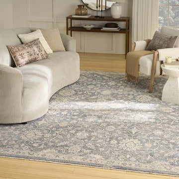Living room with a curved sofa and Nourison Retreat Blue Vintage Area Rug with a floral pattern.