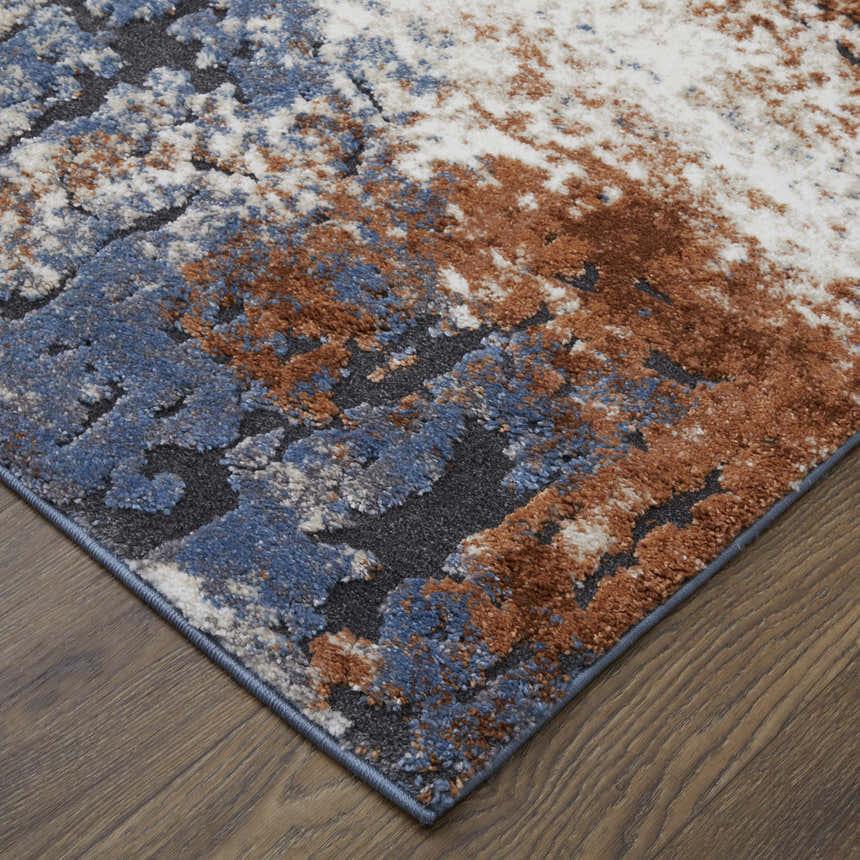 Close up of Feizy Gilmore Area Rug with a modern distressed pattern in ivory, blue, and taupe on wood floor. Corner