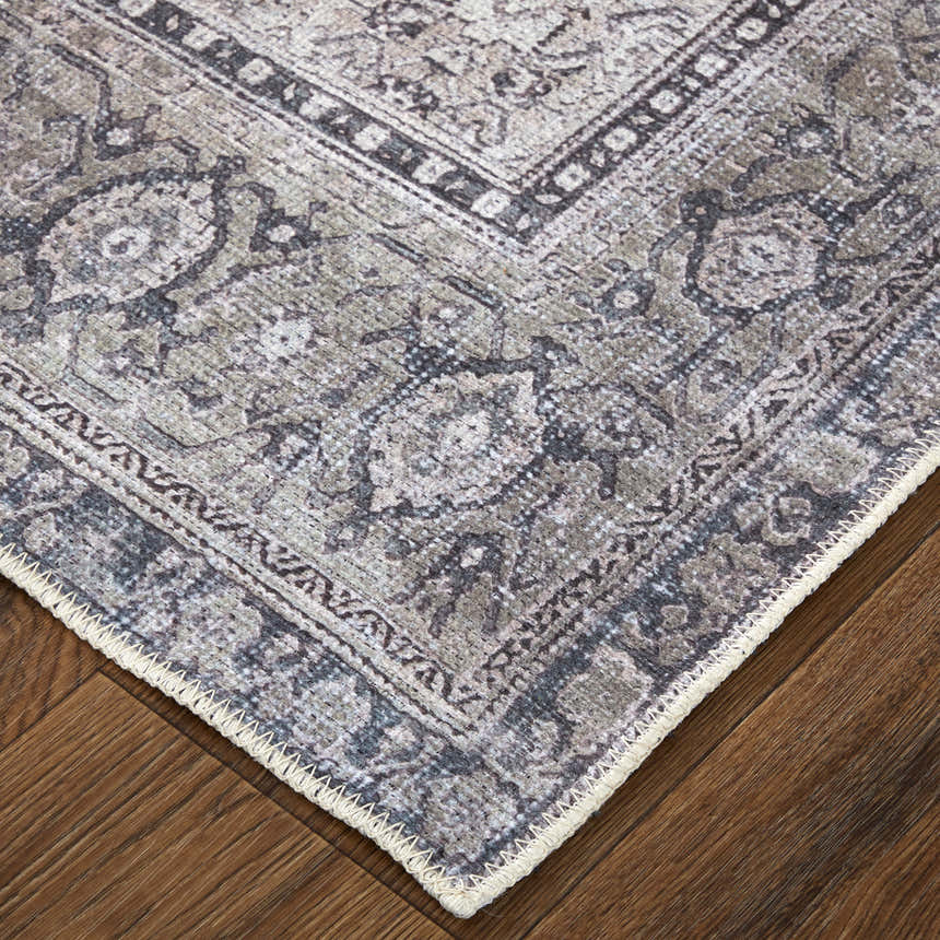 Close up of the Feizy Percy rug showing gray, ivory, and taupe medallion pattern and textured edge detail on wood floor. Corner