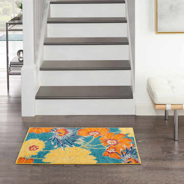 Entryway with Nourison Allur Turquoise Multicolor rug, floral pattern. Gray stairs, wood floors, and white bench.
