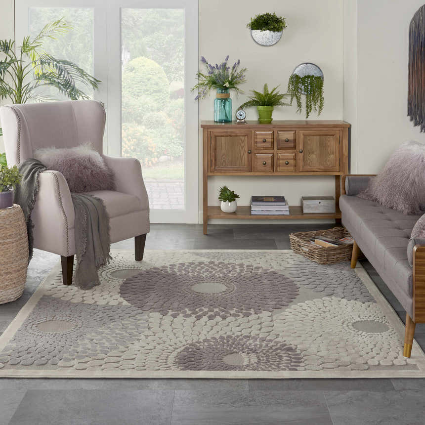 Living room with a grey sofa and the Nourison Graphic Illusions Grey Mid-Century Modern Area Rug with a floral pattern.