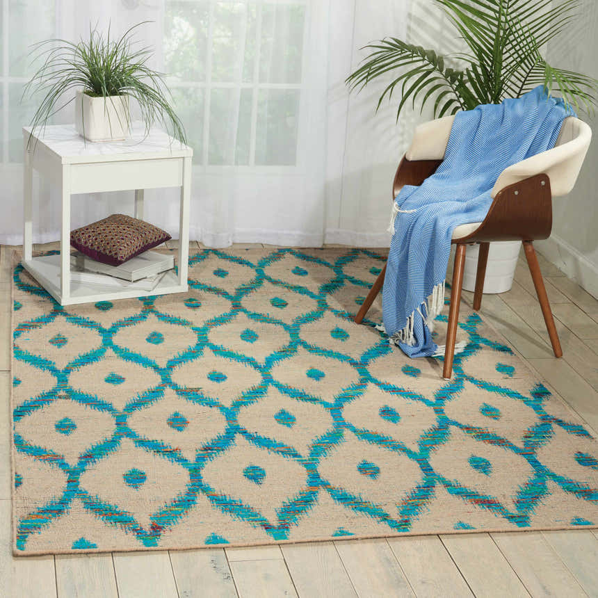 Living room scene with a Nourison Spectrum Beige Turquoise rug, chair with blue throw, and white side table.
