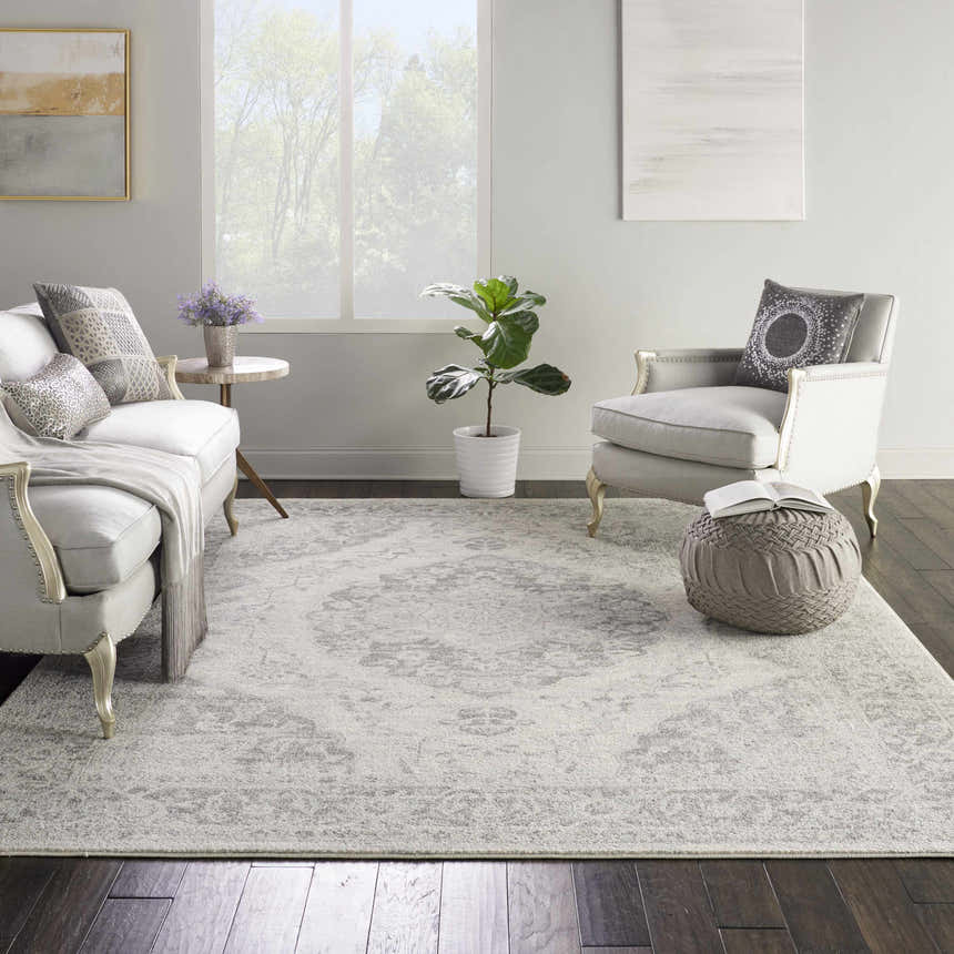 Living room scene with a Nourison Tranquil Ivory Grey Vintage rug, white sofa, chair, and dark wood floors.