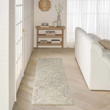 Living room scene with a DKNY Pure Angles Grey rug, white sofa, wood floors, and neutral decor.