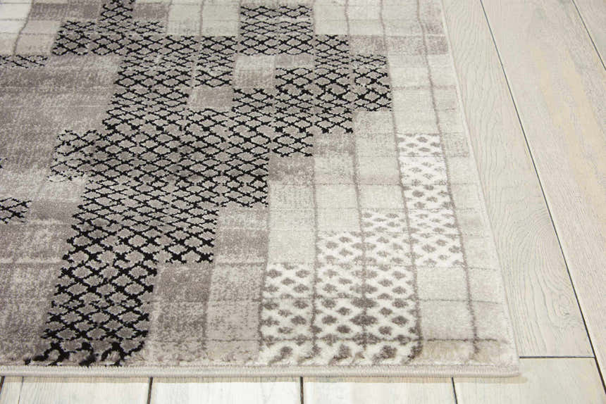 Close-up of the Nourison Soho Grey rug, showcasing its geometric block pattern and subtle gray tones on a light wood floor.