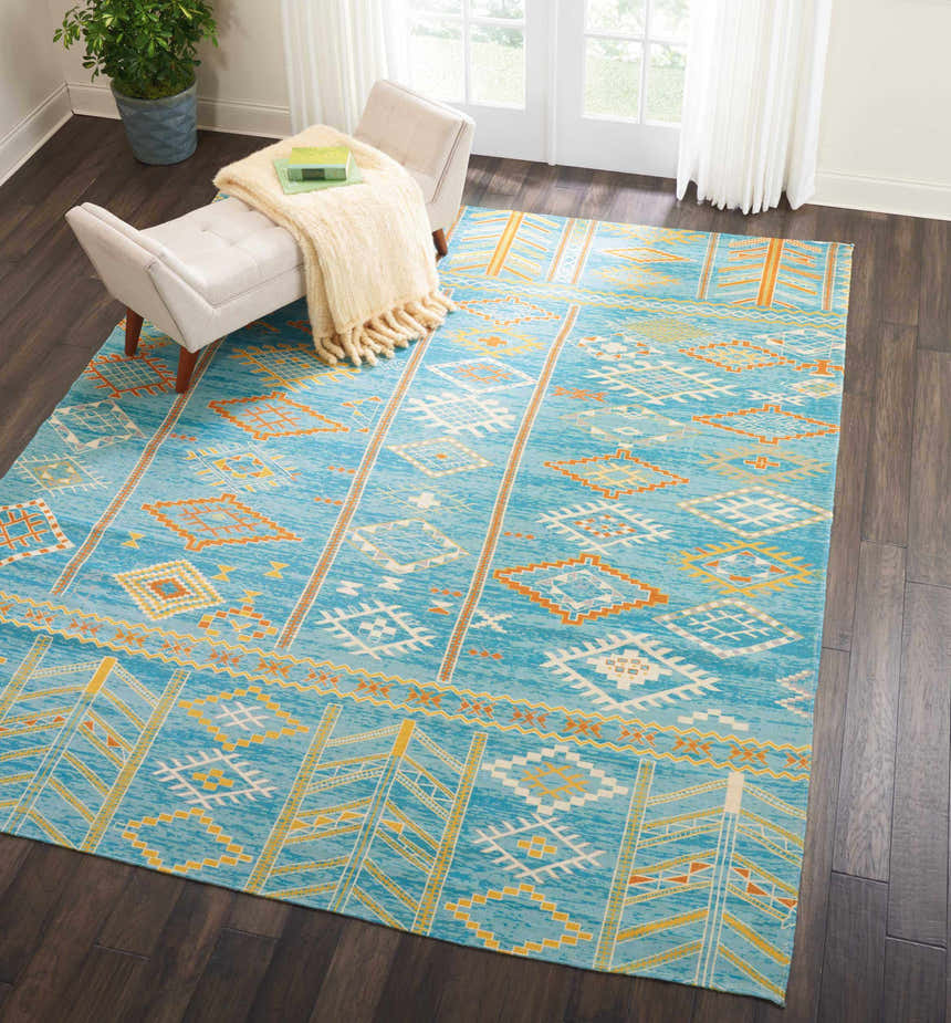 Living room scene with Nourison Madera Sky Blue Tribal rug, white bench, dark wood floors, and bright natural light.