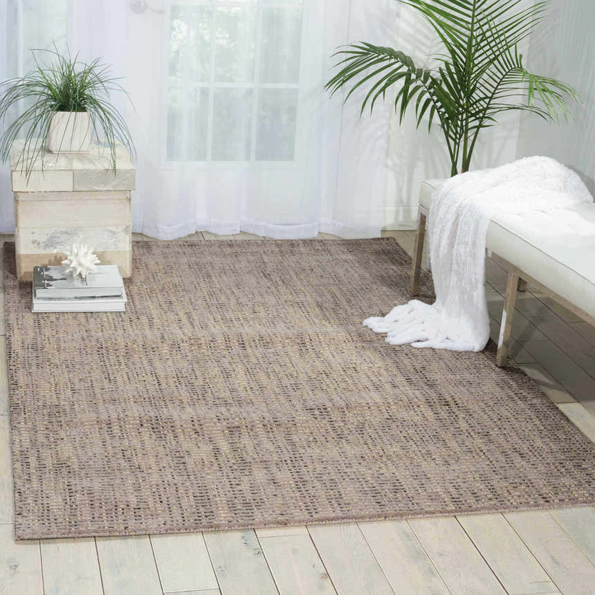 Light, airy room with Barclay Butera Intermix Smoke rug, white bench, and plants. Gray wool rug on wood floor.