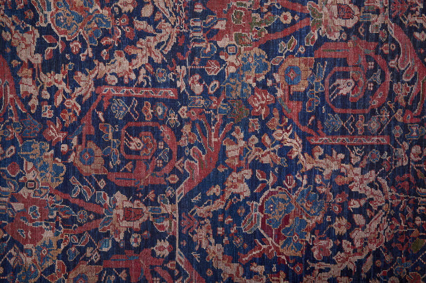 Close-up of the Feizy Rawlins rug. Transitional oriental design in blue, red, and tan with floral and geometric patterns. Texture