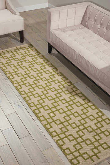 Living room scene with a Barclay Butera Maze Moss runner rug, blush sofa, and whitewashed wood floors.