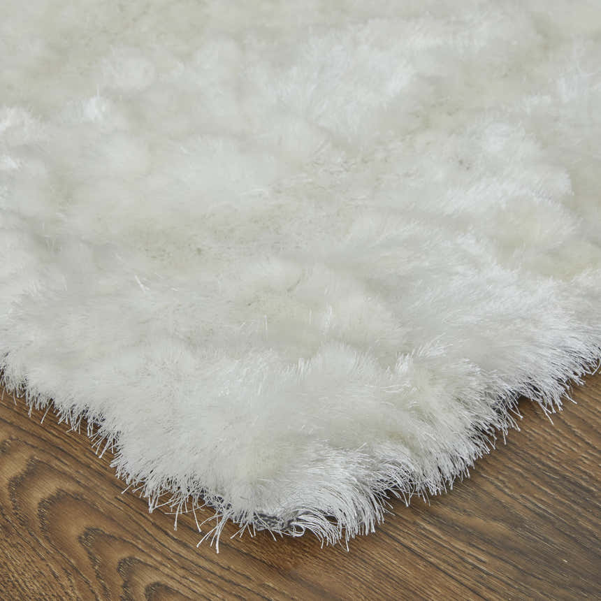 Close-up of the Feizy Indochine Modern Solid White Area Rug showing its plush texture and shaggy pile on a wood floor. Corner