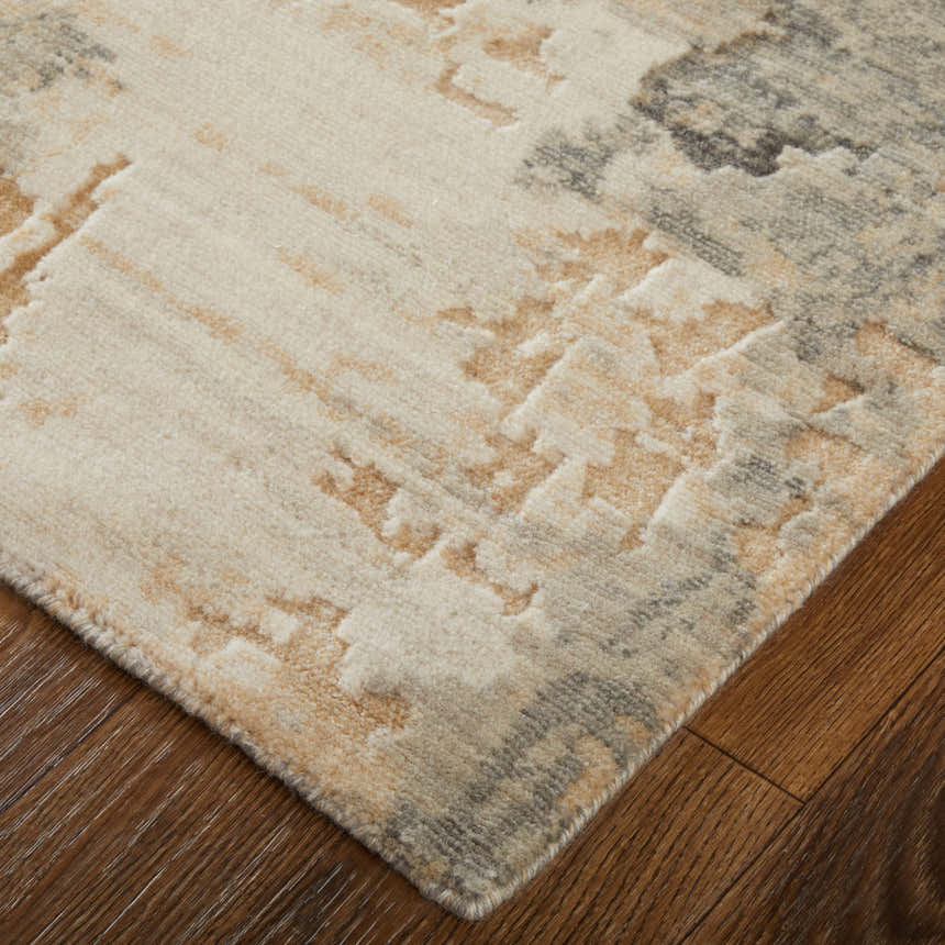 Close up of the Feizy Jaxson rug showing its gray, tan, and ivory abstract pattern and soft texture on wood floor. Corner