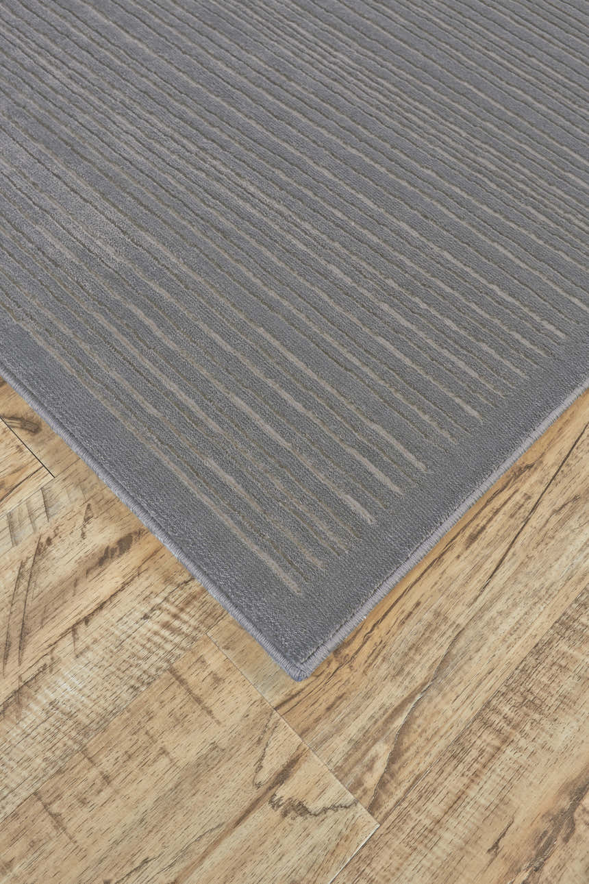 Close-up of Feizy Melina rug in blue, gray, and taupe. Modern design with subtle striped pattern and soft texture on wood floor. Corner