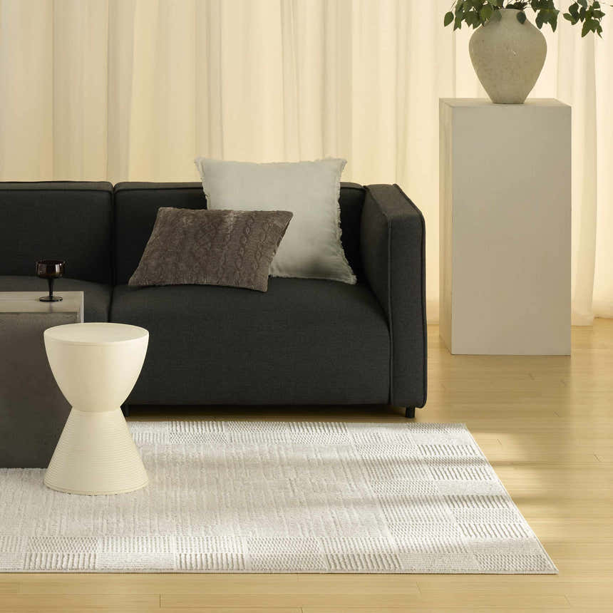 Living room scene with a Nourison Nordic Ivory Grey rug, dark sofa, and neutral decor.