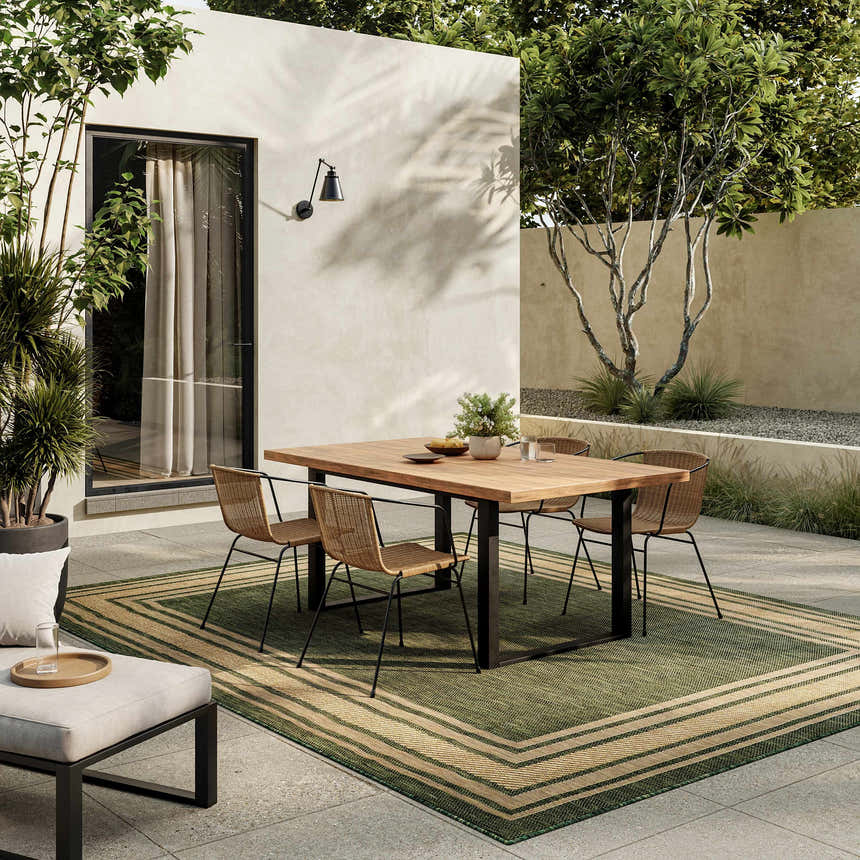 Outdoor patio scene with a wood table and the green Nourison Horizon area rug.