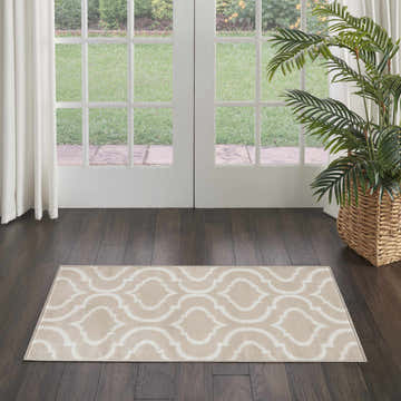 Entryway with Nourison Jubilant Beige rug, dark wood floors, white doors to garden, palm in basket. Contemporary style.